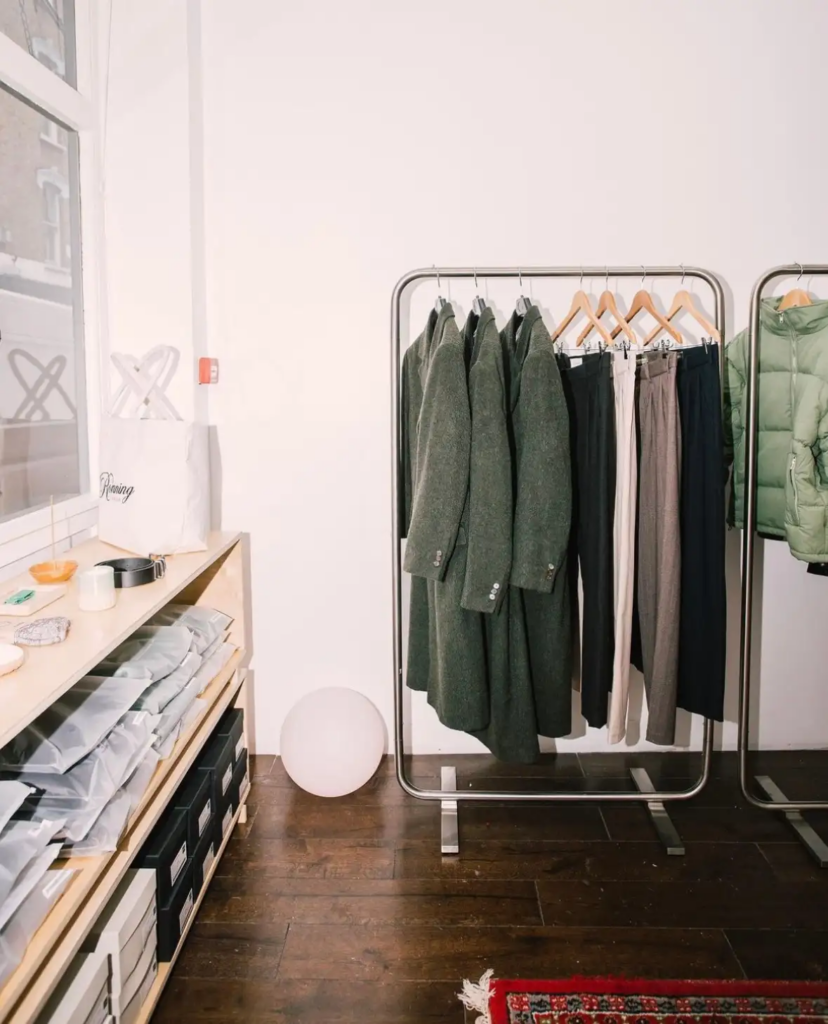 Minimalist clothing rack with coats and pants in a boutique interior.