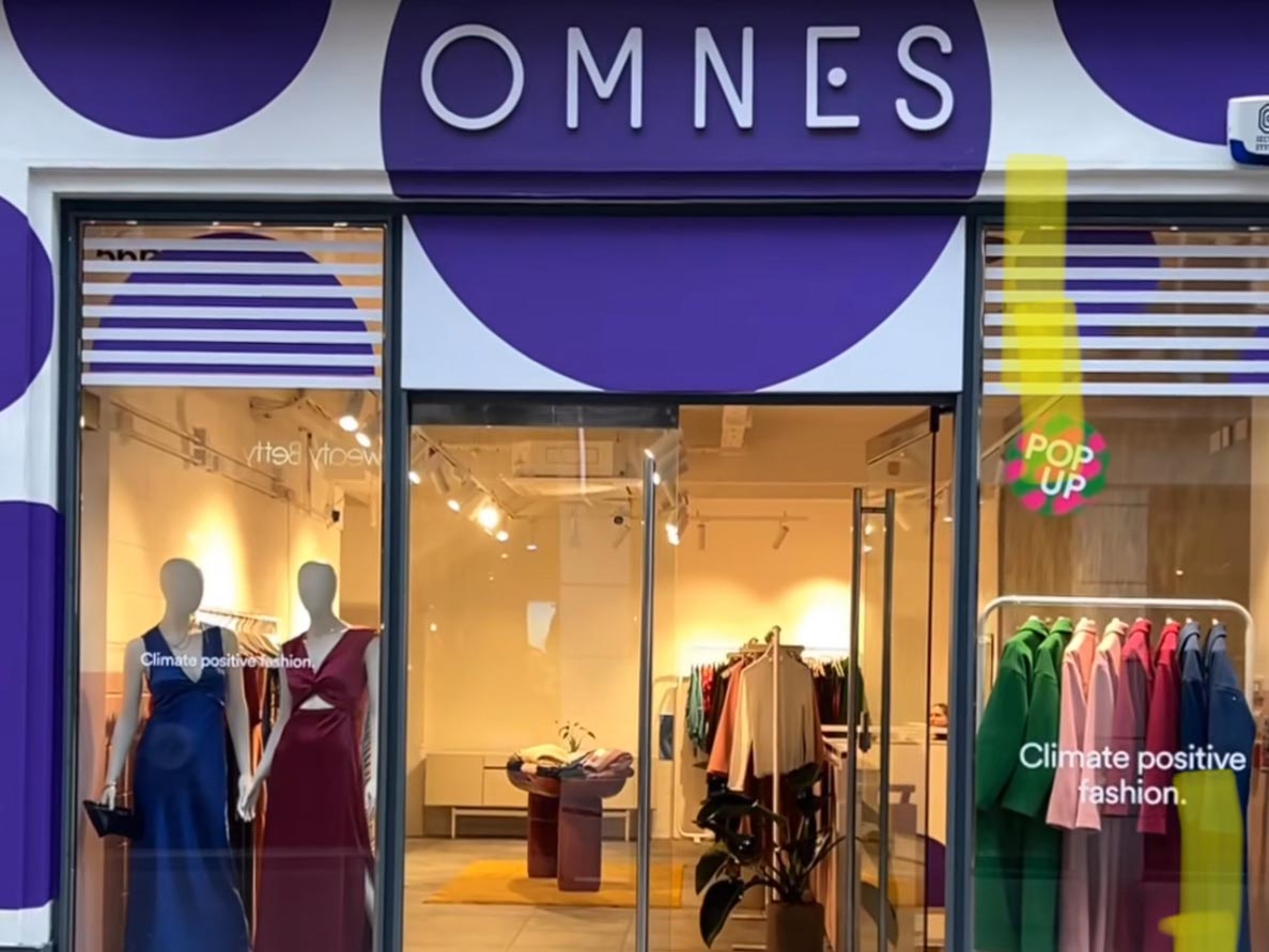 OMNES fashion store front with mannequins and eco-friendly clothes.