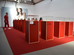 Fashion exhibit with handbags on display and visitor.