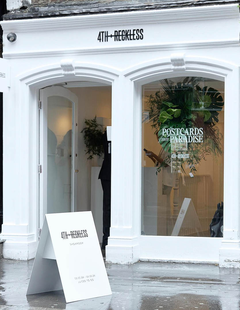 A pop-up shop interior with clothing racks and a neon sign that reads "4th and Reckless