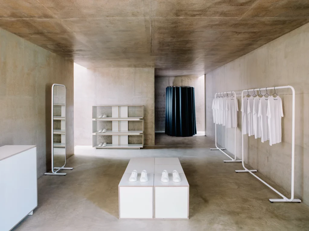 Minimalist clothing store with shoes and white shirts.