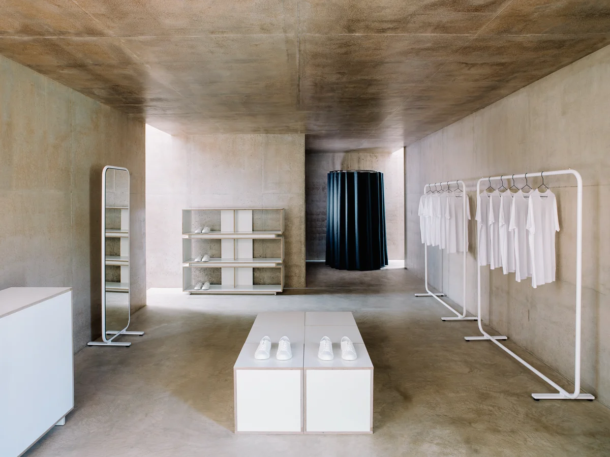 Minimalist clothing store with shoes and white shirts.