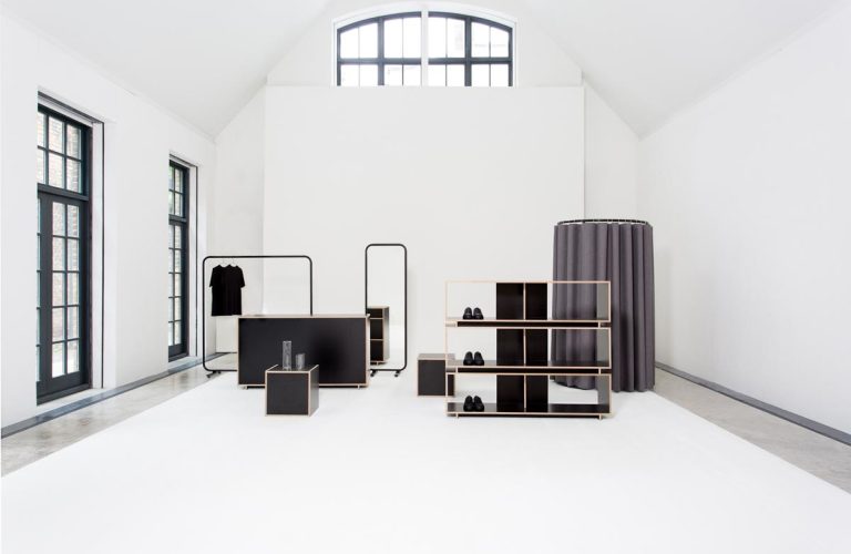 Minimalist retail interior with clothing racks, shelves, and black accents.