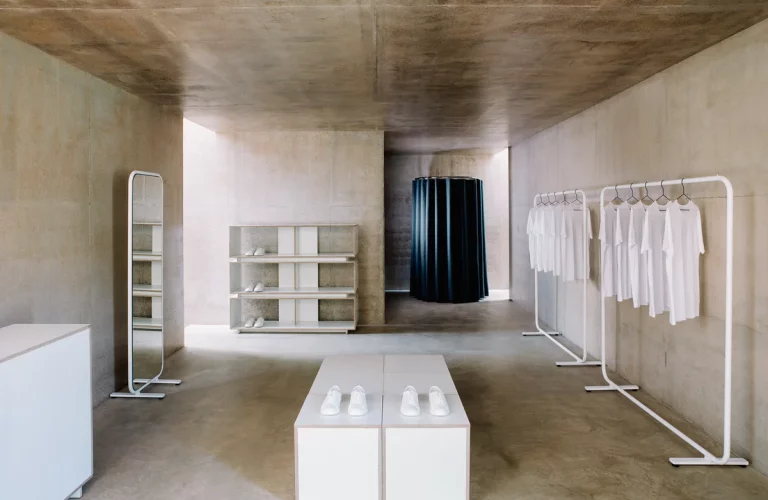 Minimalist clothing store with shoes and white shirts.
