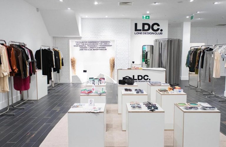 Fashion boutique interior with clothing racks and accessories displays.