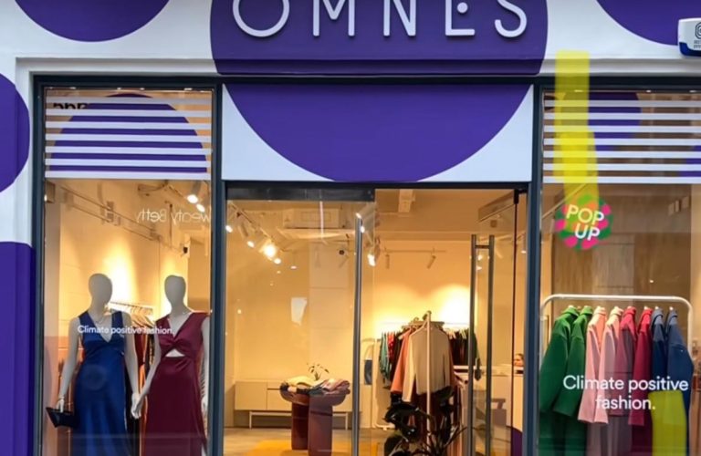 OMNES fashion store front with mannequins and eco-friendly clothes.