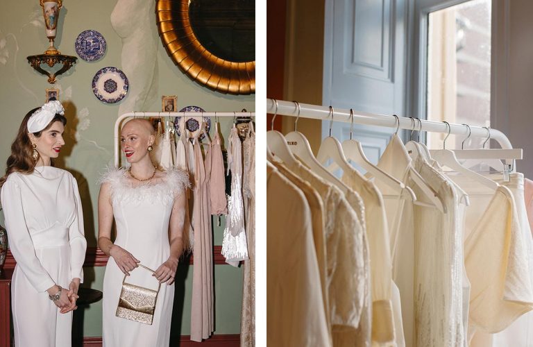 Two women in elegant vintage dresses chatting; a rack of bridal gowns by a window.