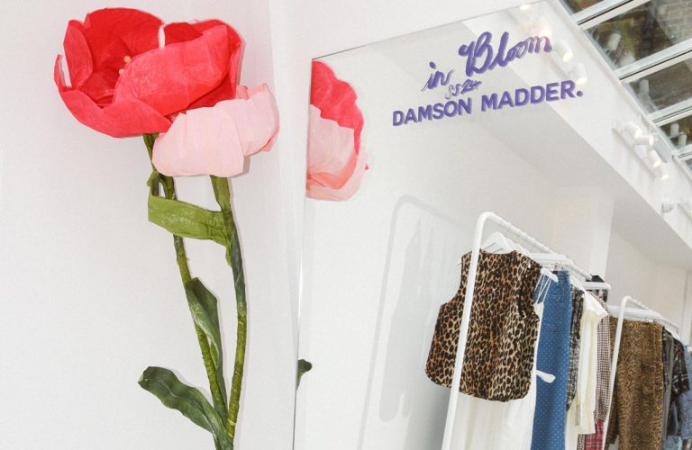 Oversized paper flowers in a boutique with racks of stylish clothes in the background.